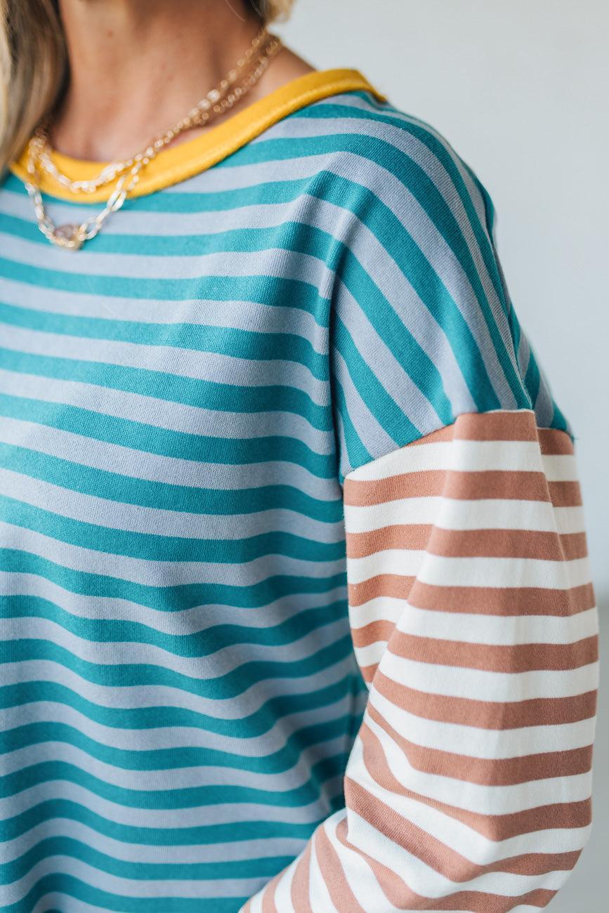 Close-up of a person wearing a striped shirt with blue, white, yellow, and brown colors.