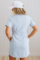 Person wearing a light blue dress and white cap indoors