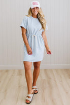 Woman wearing a light blue dress and white cap with 'USA' text on a wooden floor.