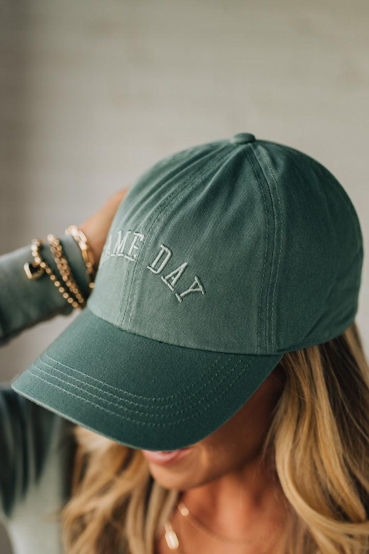 Green cap with 'ONE DAY' text worn by a person, blurred background