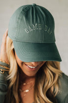 Person wearing a green 'GAME DAY' cap against a neutral background