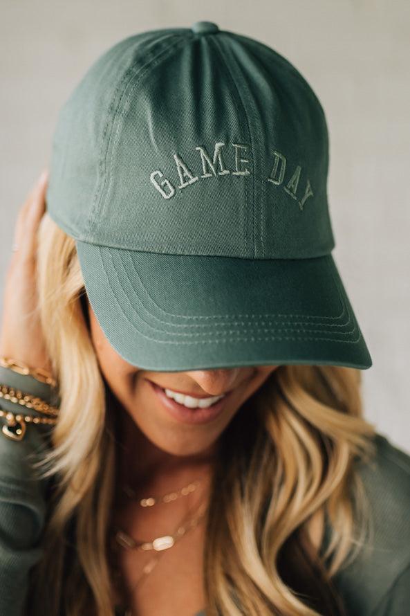 Person wearing a green 'GAME DAY' cap against a neutral background