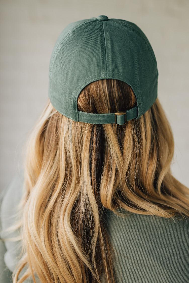 Person wearing a green cap with long blonde hair