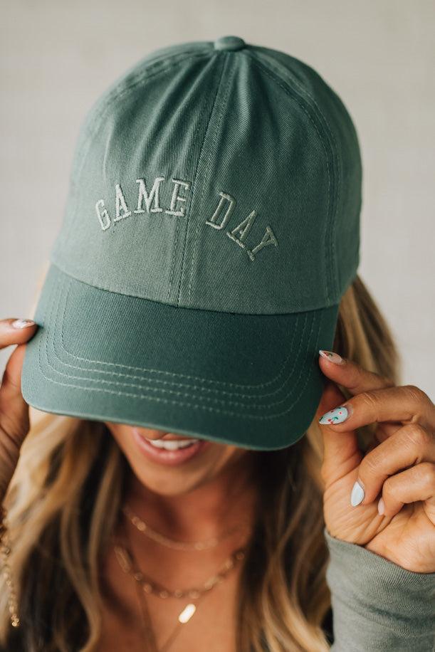 Green 'GAME DAY' cap worn by a person with a neutral background