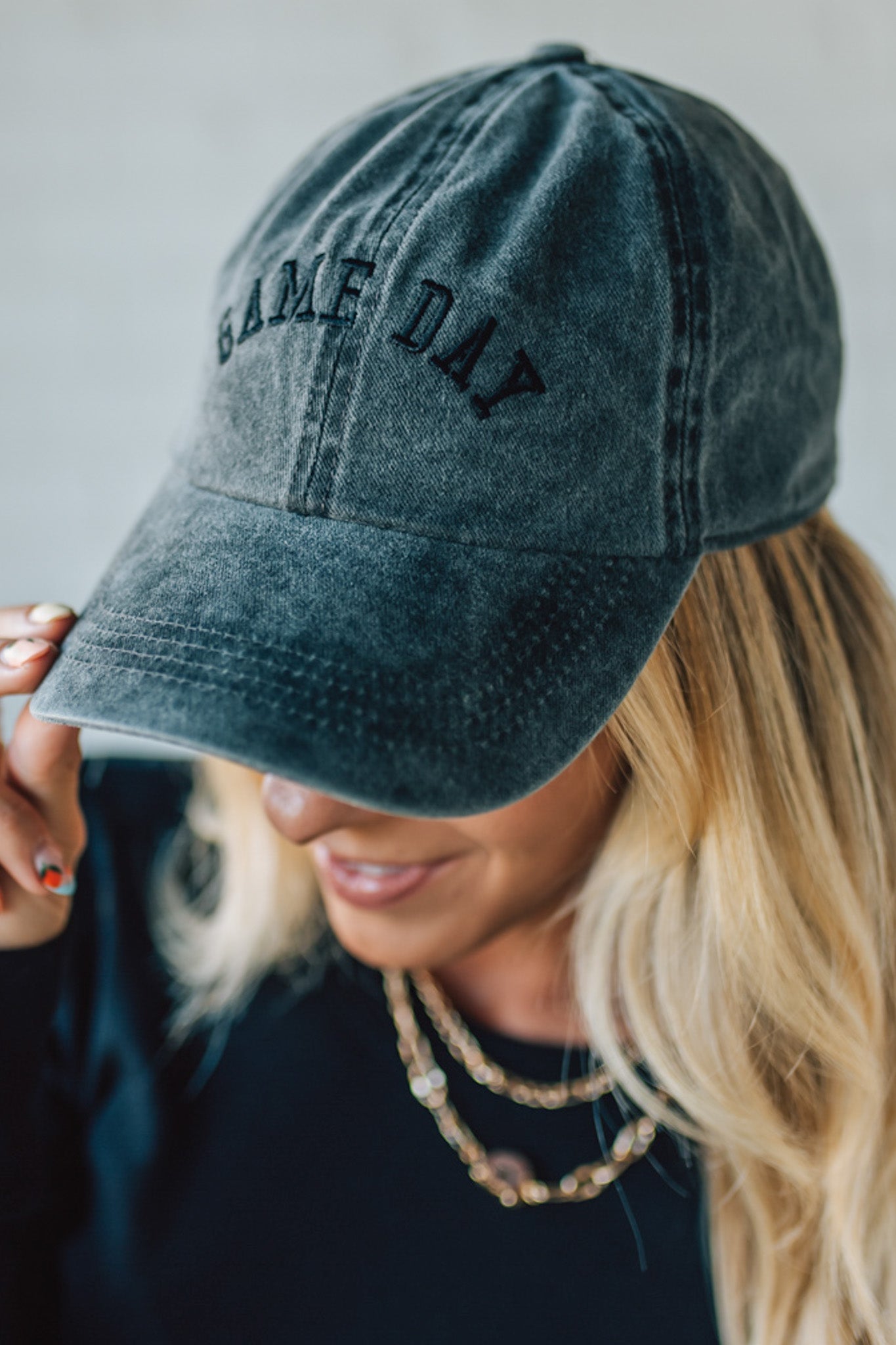 Person wearing a denim cap with 'GAME DAY' text against a neutral background