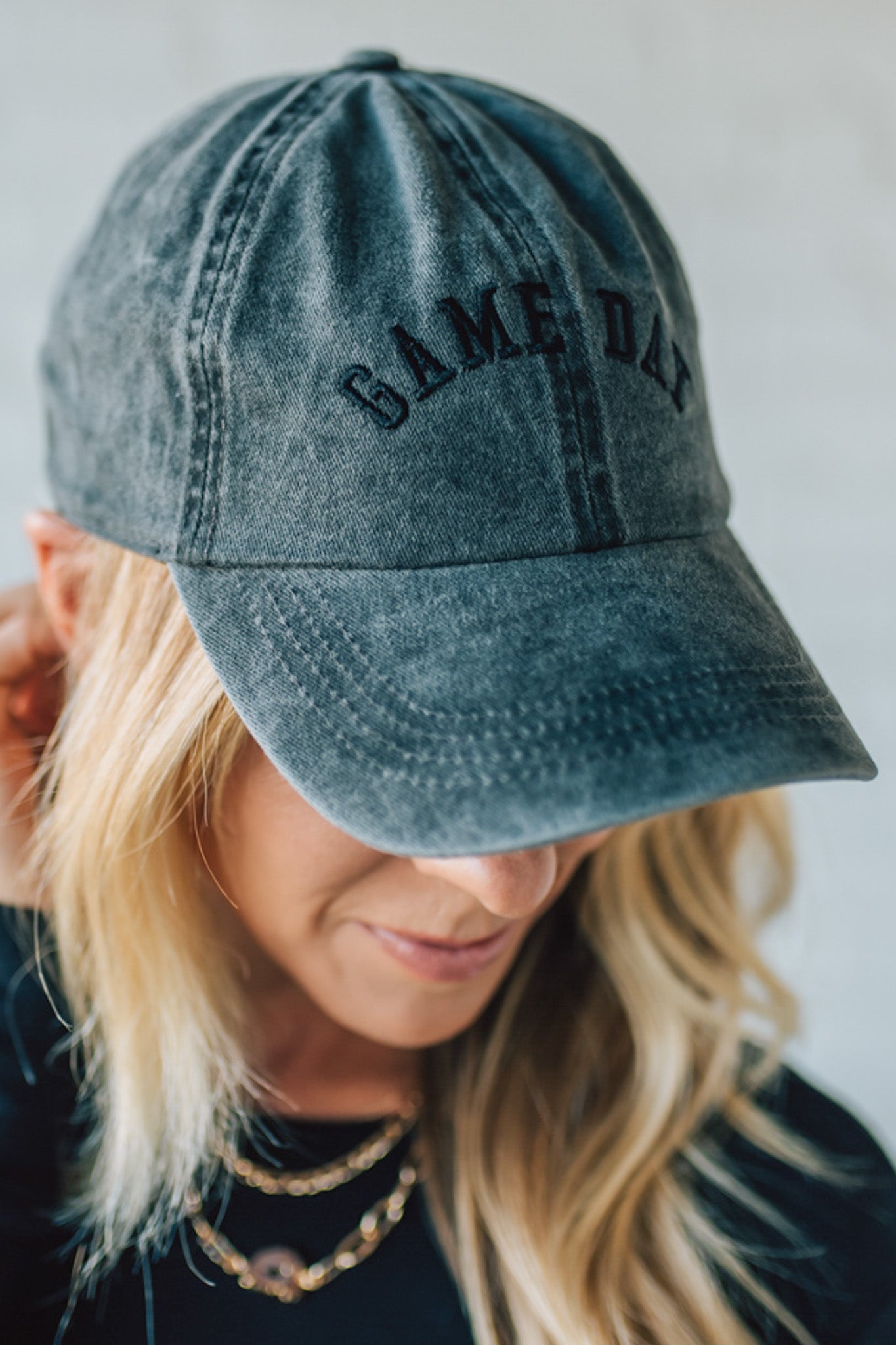 Person wearing a denim cap with 'GAME DAY' text against a neutral background