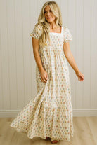 Woman wearing a floral dress against a plain wall.