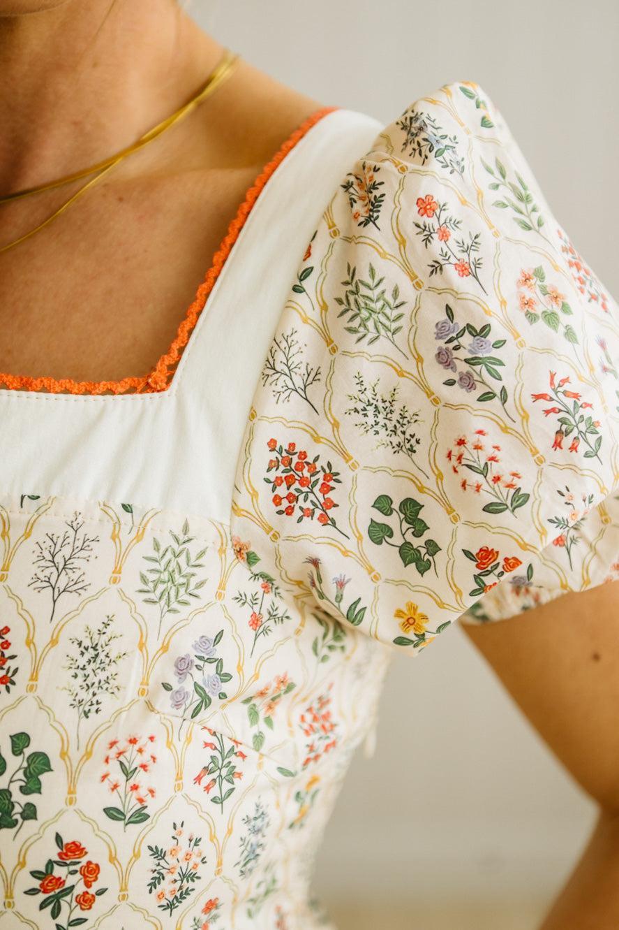 Close-up of a floral patterned garment with orange trim on a neutral background