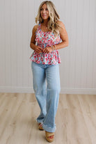 Woman wearing a floral top and light blue jeans standing on a wooden floor.