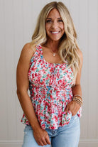 Woman wearing a floral top and jeans against a neutral background