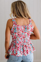 Woman wearing a floral sleeveless top and blue jeans against a neutral background