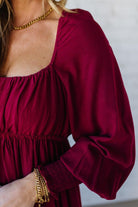 Blonde Woman Wearing a Gathered Long Sleeve Maxi Dress in the color Cherry Merlot.