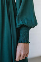 Blonde Woman Wearing a Gathered Long Sleeve Maxi Dress in the color Deep Forest.