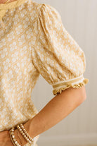 Close-up of a person wearing a patterned blouse with puff sleeves against a neutral background