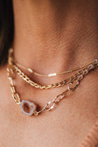 Close-up of a person wearing multiple gold necklaces with a focus on texture and layering.