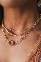 Close-up of a person wearing gold necklaces with a textured background