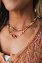 Close-up of a person wearing a gold chain necklace with a blurred background