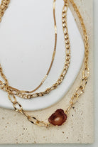 Gold chain necklaces on a white stone surface