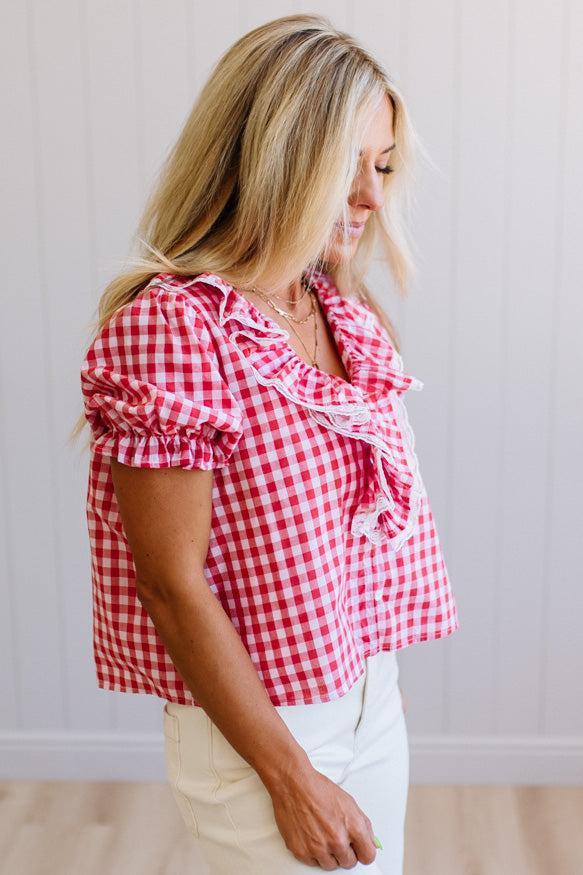 Woman wearing a red and white checkered blouse against a plain background