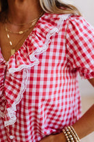 Red and white checkered blouse with ruffled details on a person.