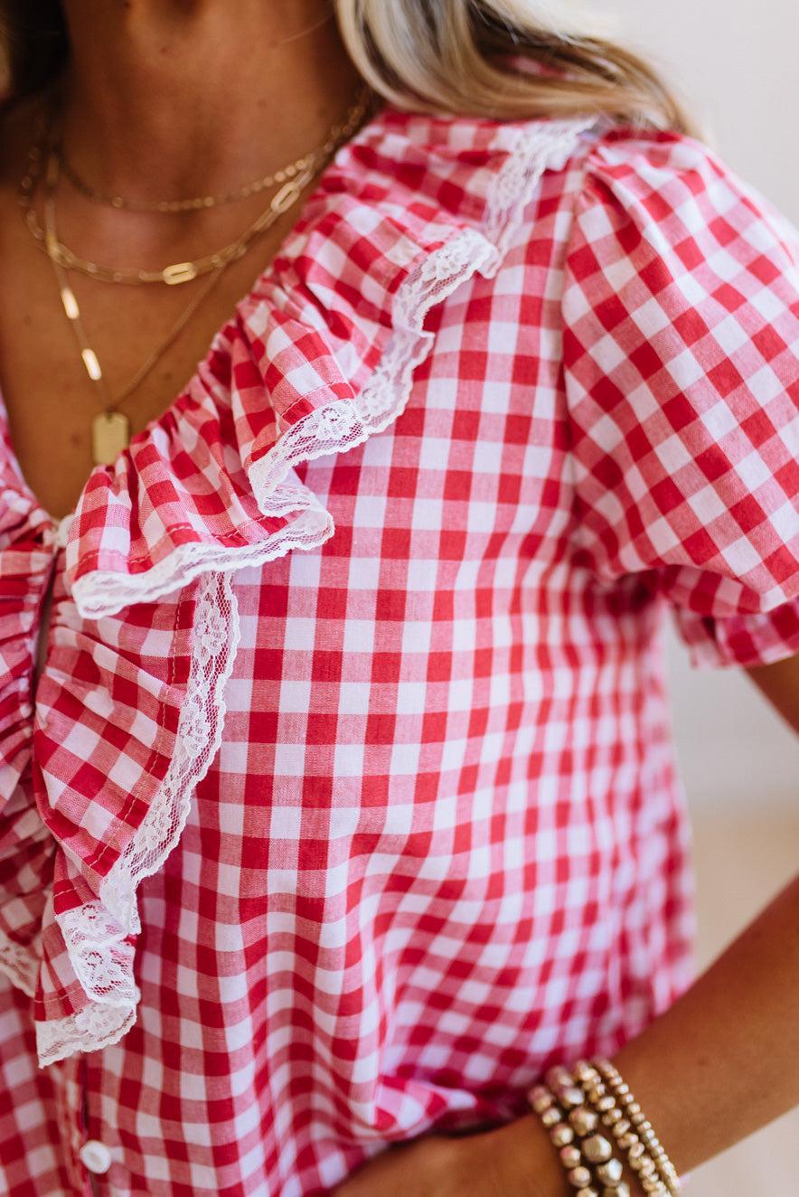 Red and white checkered blouse with ruffled details on a person.
