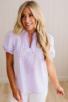 Blonde woman wearing a lavender and white gingham top with scallop edge trim and puff sleeves.