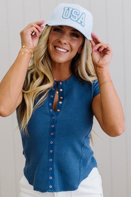 Woman wearing a blue 'USA' cap and blue button-up shirt against a neutral background