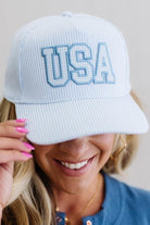 Blue and white striped cap with 'USA' text held by a person against a neutral background