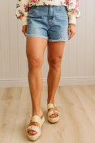 Person wearing denim shorts and sandals on a wooden floor.