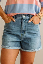 Person wearing a striped shirt and denim shorts with a neutral background