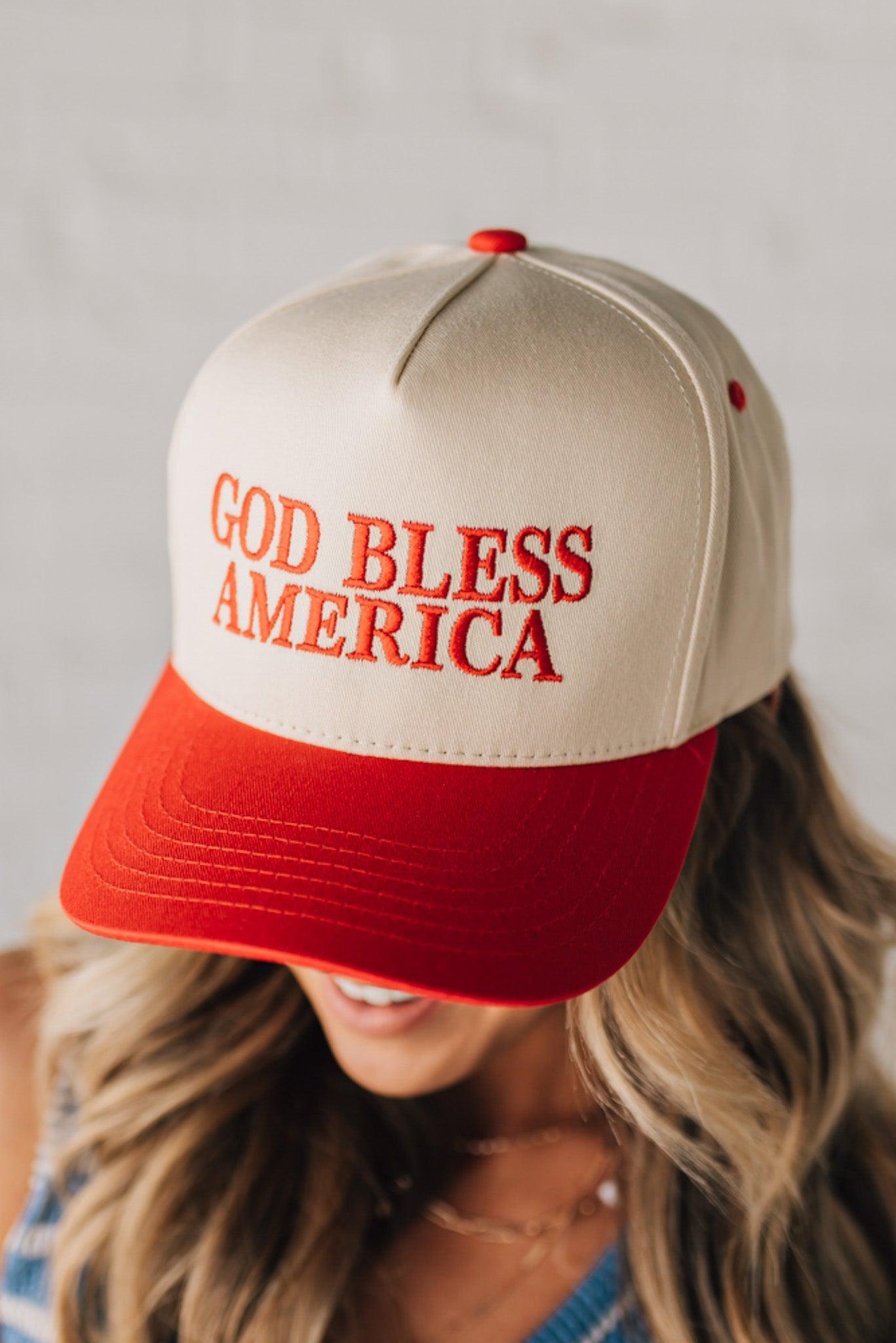 Blonde woman wearing a two tone cream and red trucker hat with GOD BLESS AMERICA embroidered at the front.