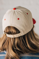 Blonde woman wearing a two tone cream and red trucker hat with GOD BLESS AMERICA embroidered at the front.