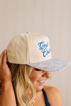 Beige cap with blue text worn by a person, against a plain background