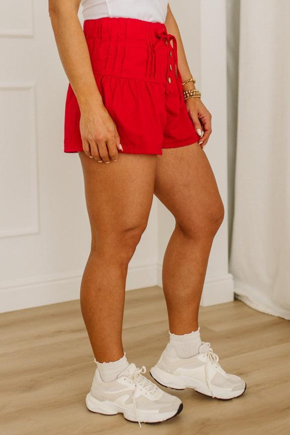Person wearing red shorts and white sneakers indoors.