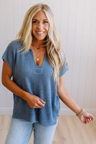Blonde woman wearing a short sleeve v-neck ribbed texture sweater with center patch accent in blue.