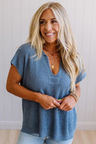 Blonde woman wearing a short sleeve v-neck ribbed texture sweater with center patch accent in blue.