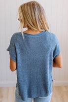 Blonde woman wearing a short sleeve v-neck ribbed texture sweater with center patch accent in blue.