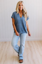 Blonde woman wearing a short sleeve v-neck ribbed texture sweater with center patch accent in blue.