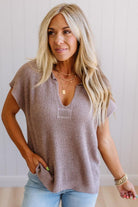 Blonde woman wearing a short sleeve v-neck ribbed texture sweater with center patch accent in mocha.