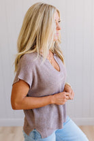 Blonde woman wearing a short sleeve v-neck ribbed texture sweater with center patch accent in mocha.