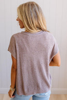 Blonde woman wearing a short sleeve v-neck ribbed texture sweater with center patch accent in mocha.