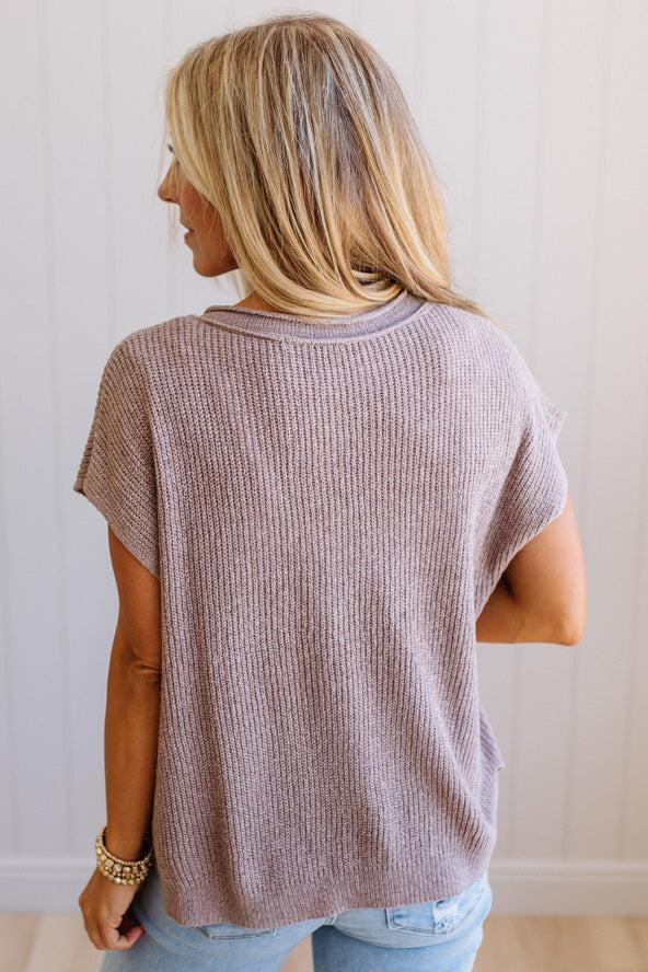 Blonde woman wearing a short sleeve v-neck ribbed texture sweater with center patch accent in mocha.
