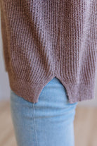 Blonde woman wearing a short sleeve v-neck ribbed texture sweater with center patch accent in mocha.