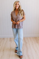 Blonde woman wearing a short sleeve v-neck ribbed texture sweater with center patch accent in mocha.