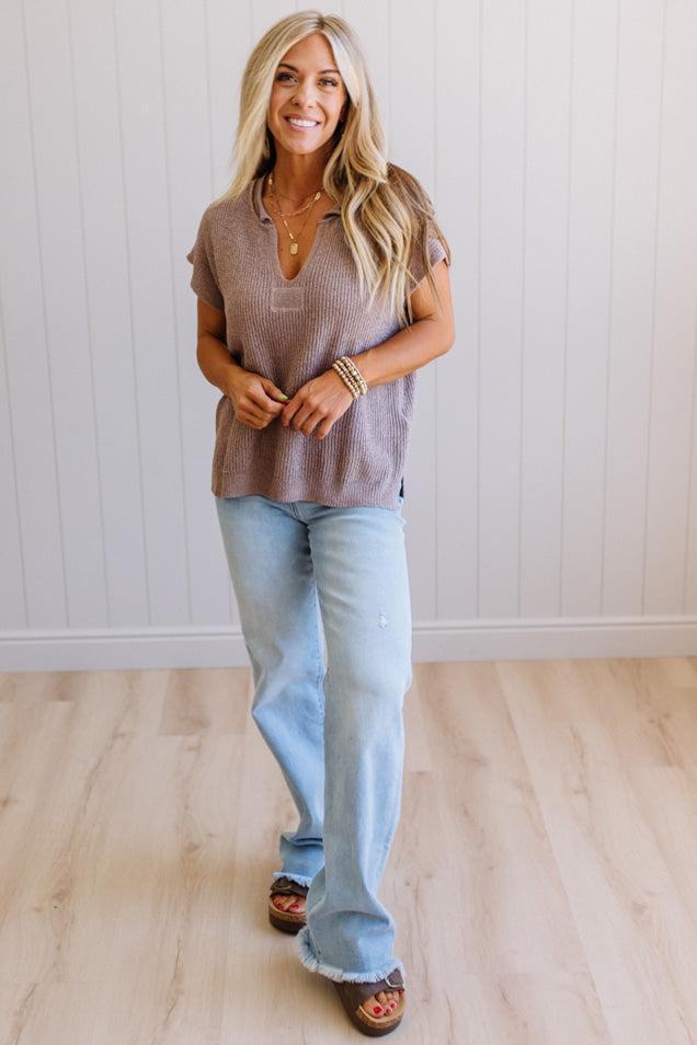 Blonde woman wearing a short sleeve v-neck ribbed texture sweater with center patch accent in mocha.