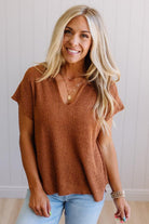 Blonde woman wearing a short sleeve v-neck ribbed texture sweater with center patch accent in rust.