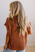 Blonde woman wearing a short sleeve v-neck ribbed texture sweater with center patch accent in rust.