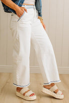 Person wearing white pants with blue trim and sandals indoors.