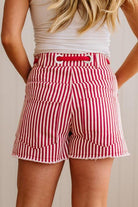 Woman wearing red and white striped shorts with red braided belt through grommets on waist. 