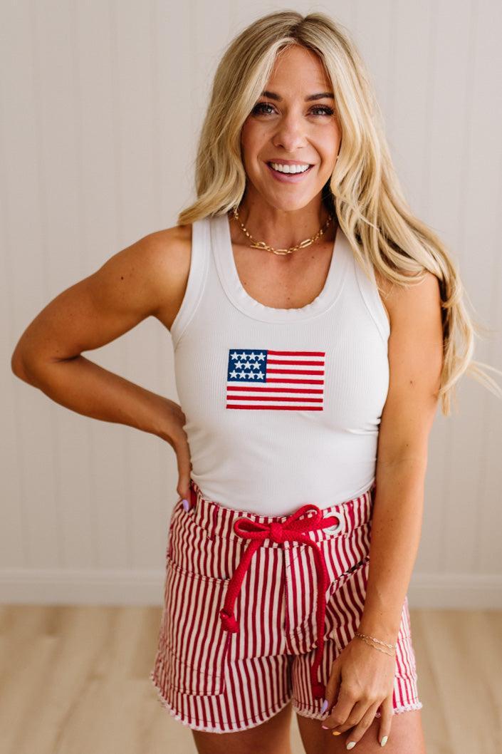 Woman wearing red and white striped shorts with red braided belt through grommets on waist. 